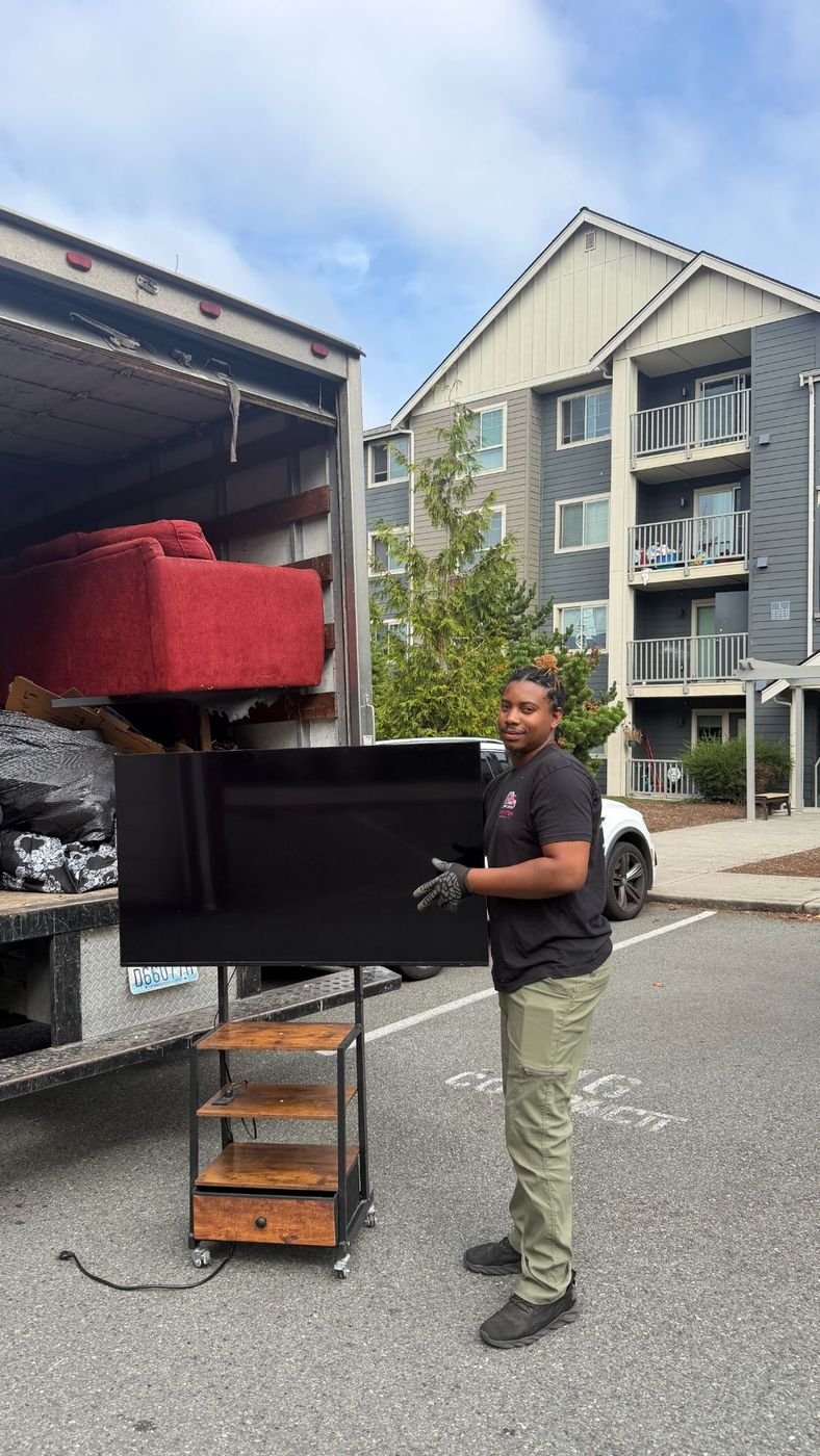 Crew loading a TV into the truck during appliance removal in Edmonds